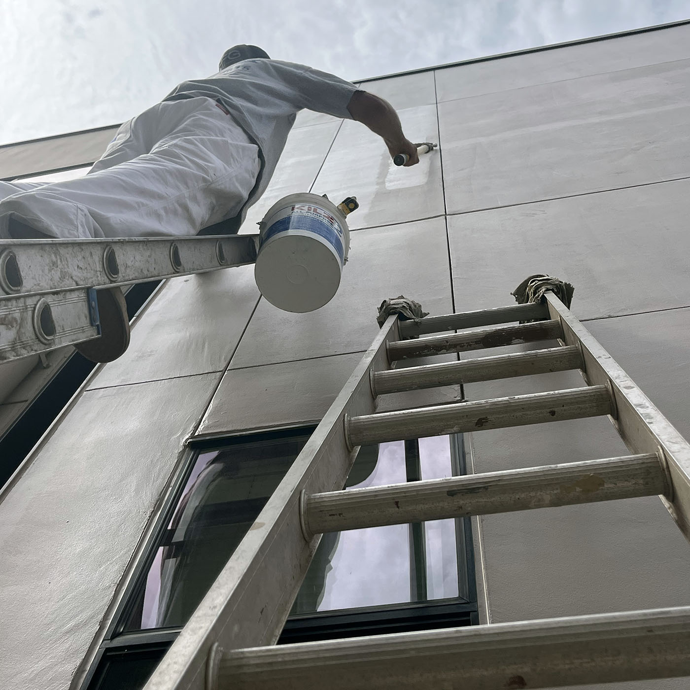 Jason Pontius painting a commercial building exterior